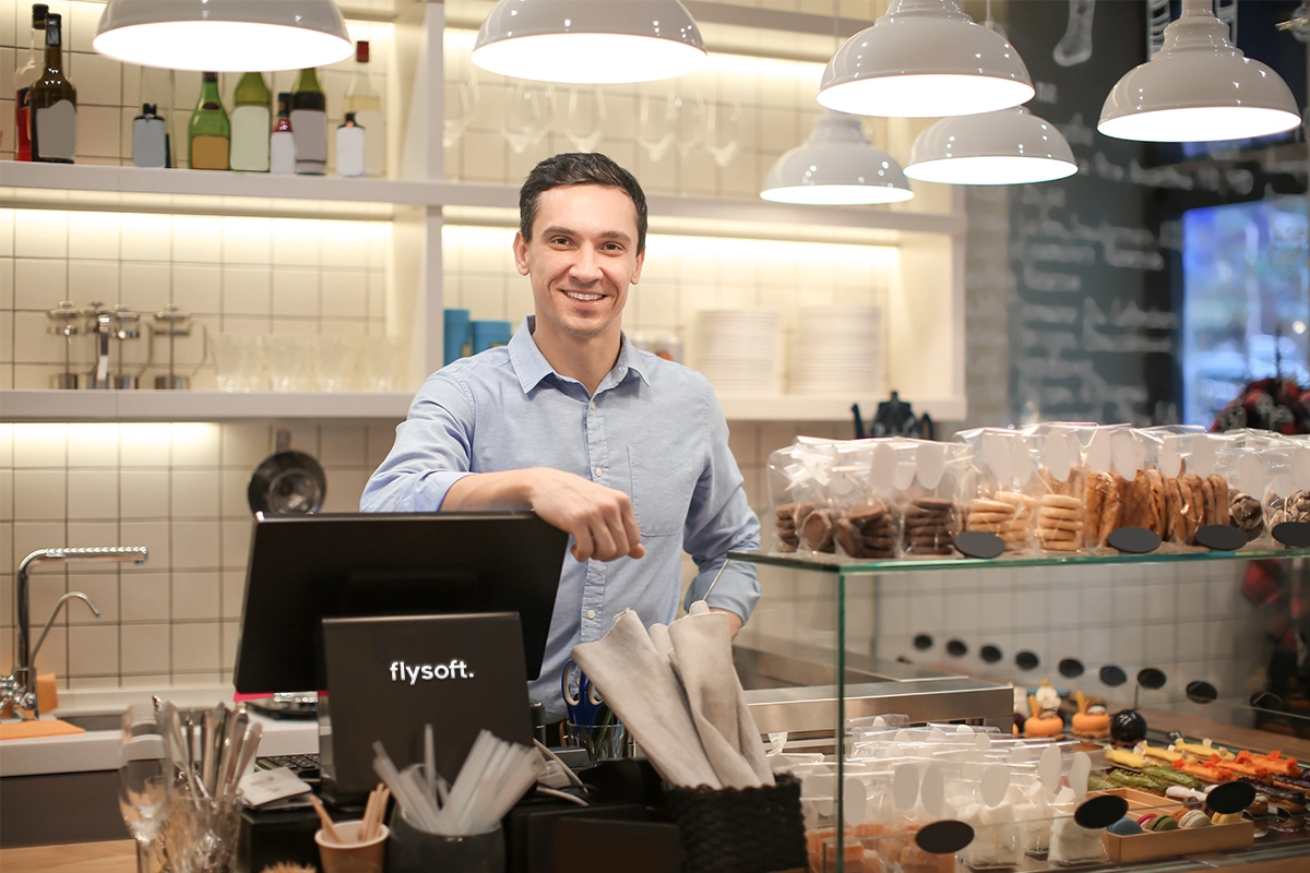 Middle aged food and beverage shop owner smiling happily after using flysofts POS machine.